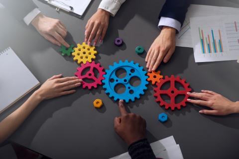 A group of people's hands holding gears. 